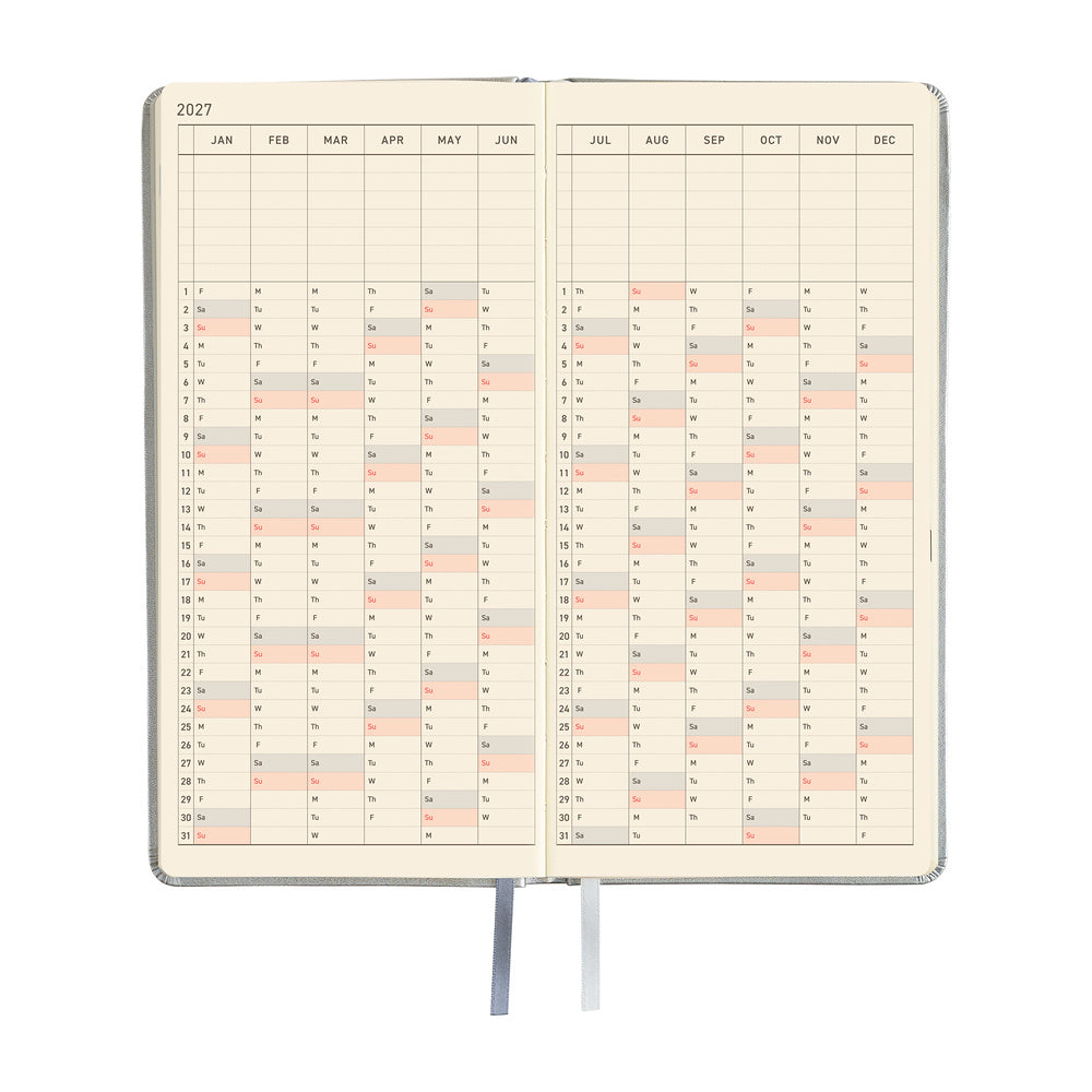 An open planner showing a yearly calendar spread with cream-colored pages and black grid lines.