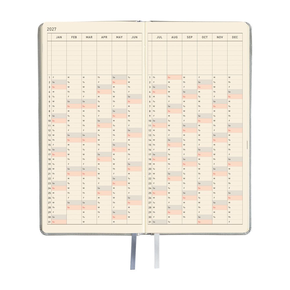 An open planner showing a yearly calendar spread with cream-colored pages and black grid lines.
