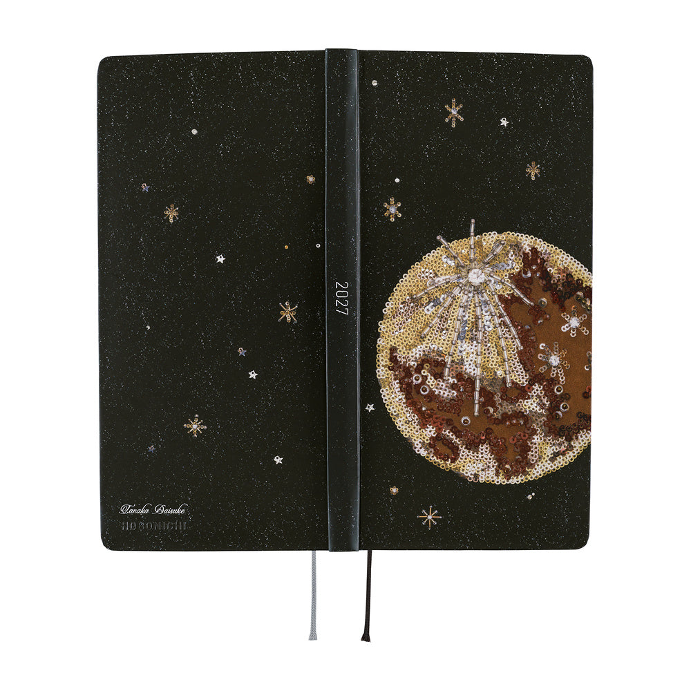 The exterior of a planner featuring a printed image of an embroidery piece crafted from countless beads, sequins, and jewels depicting the luminous moon surrounded by shining stars in the night sky.