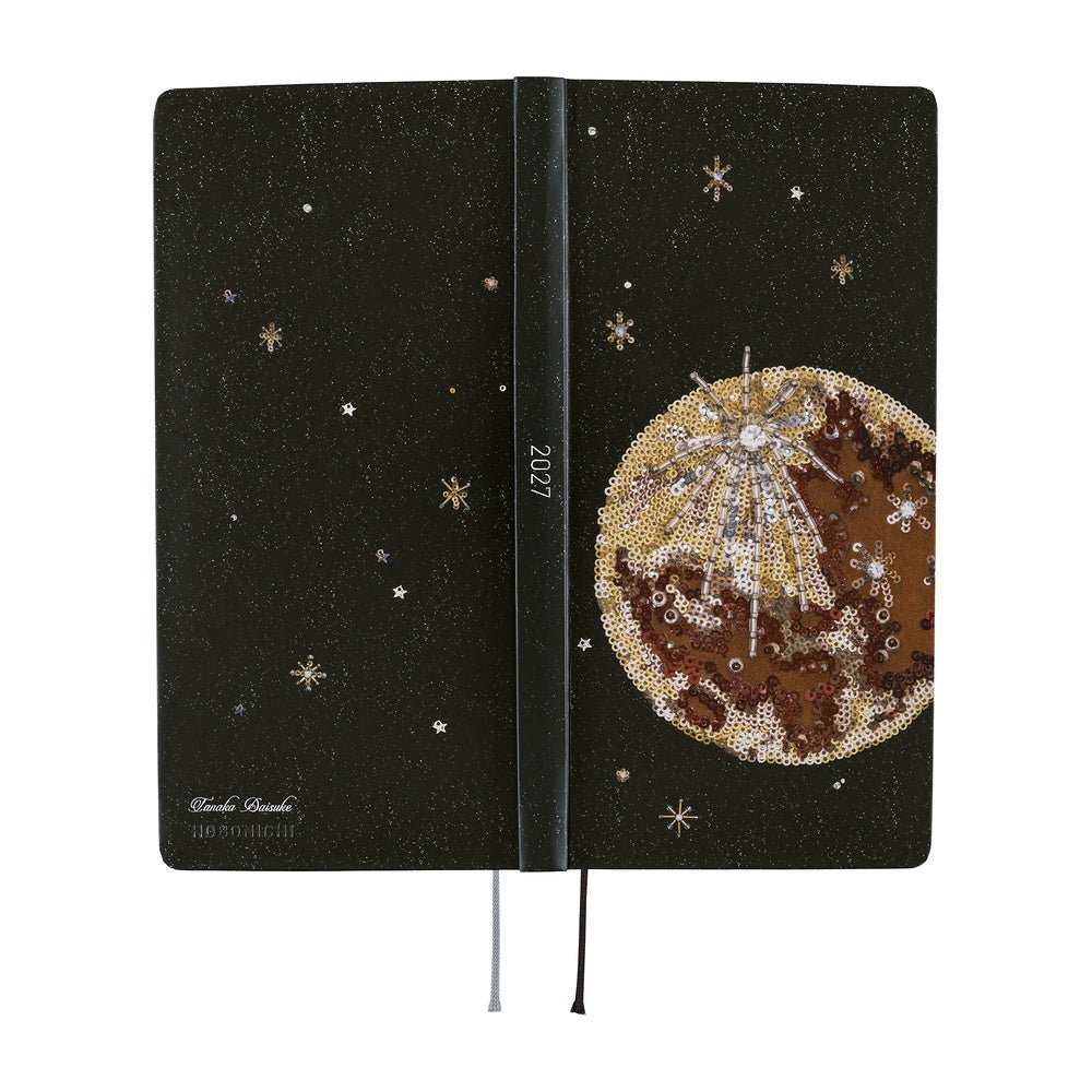 The exterior of a planner featuring a printed image of an embroidery piece crafted from countless beads, sequins, and jewels depicting the luminous moon surrounded by shining stars in the night sky.
