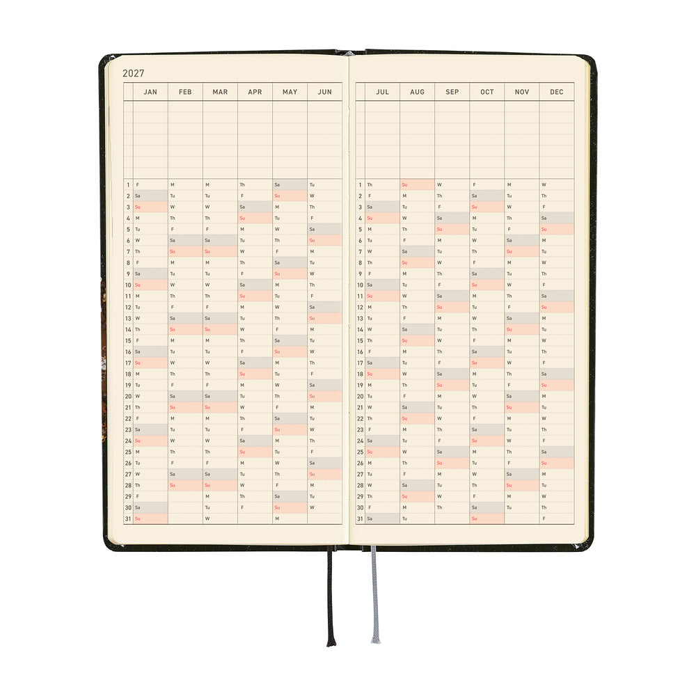 An open 2027 planner showing a yearly calendar spread. The pages are cream-colored and a black and silver ribbon bookmark hangs from the bottom center against a plain white background.