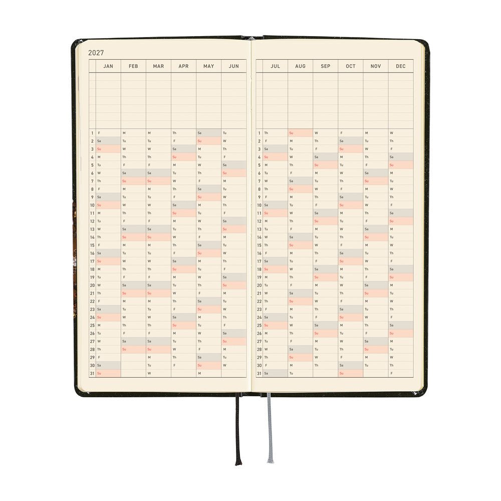 An open 2027 planner showing a yearly calendar spread. The pages are cream-colored and a black and silver ribbon bookmark hangs from the bottom center against a plain white background.