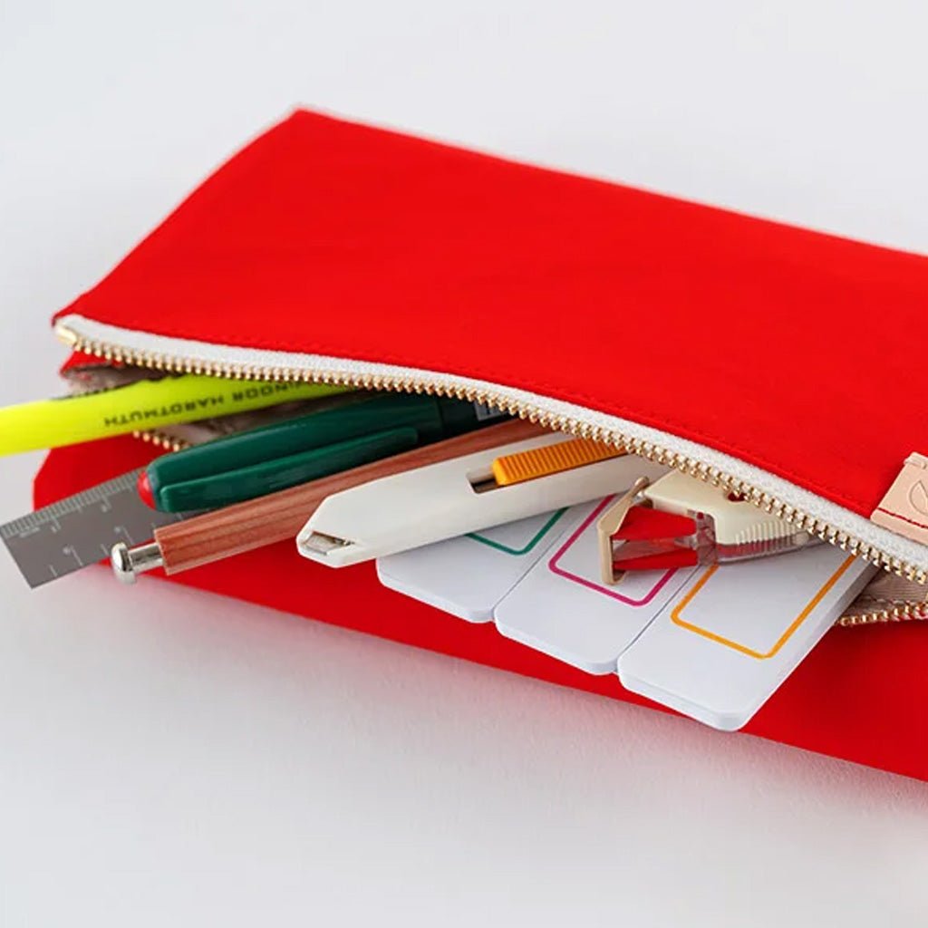 A bright red fabric pencil case with a gold zipper, shown open with various school supplies like pens, a ruler, and sticky notes peeking out, set against a clean white background.