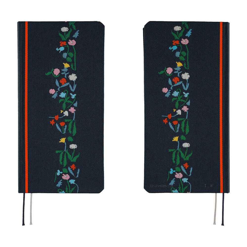 A front and back view of a dark navy blue planner with a vertical floral vine design in green, pink, blue, yellow, and white along the right side. It features a bright red band near the spine and ribbon bookmarks hanging from the bottom.