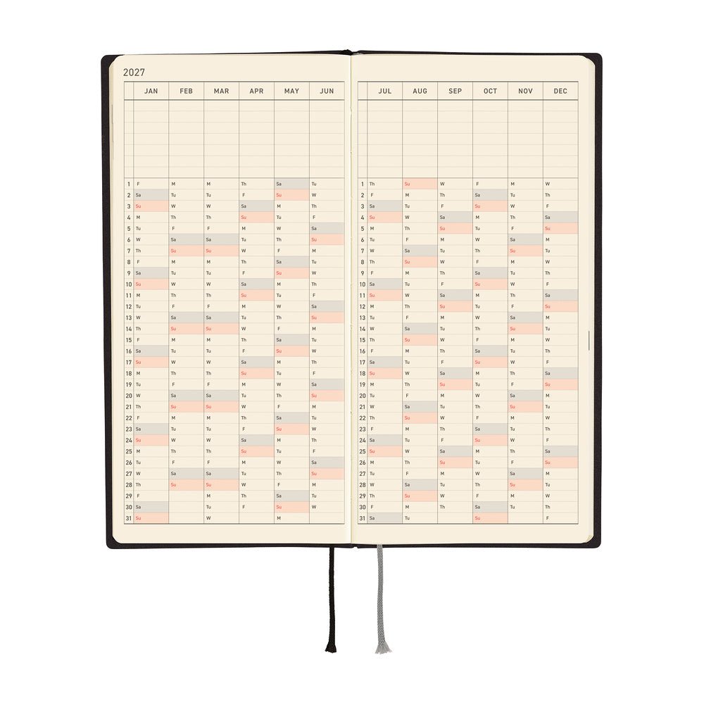 An open 2027 planner with cream-colored pages showing a yearly calendar grid, black binding, and two ribbon bookmarks, photographed on a solid white background.