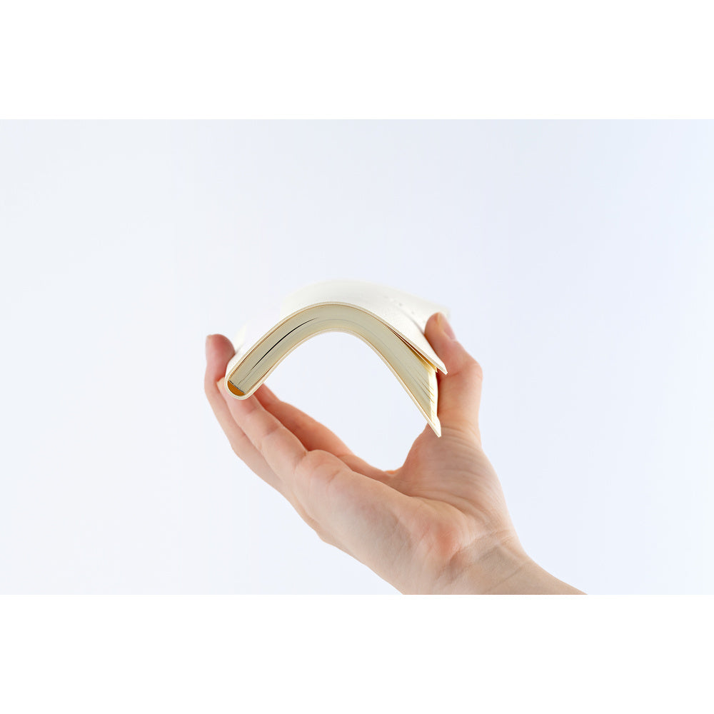 A hand holding a flexible, cream-colored planner that curves upward.