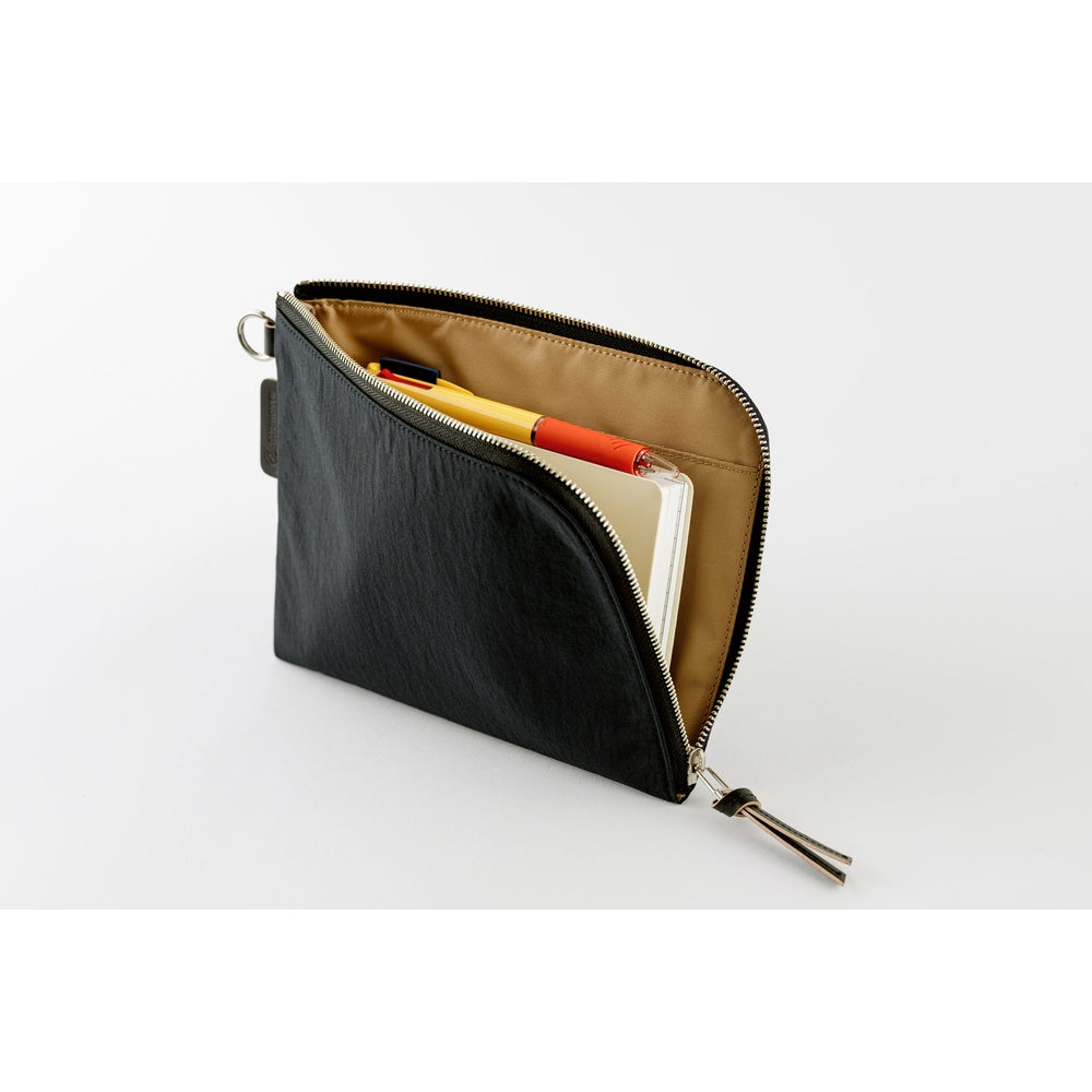 A black textured zippered pouch shown open, revealing a tan interior with pens and a notebook inside. The pouch has a silver zipper and a small black tag on the side, photographed on a clean white background.
