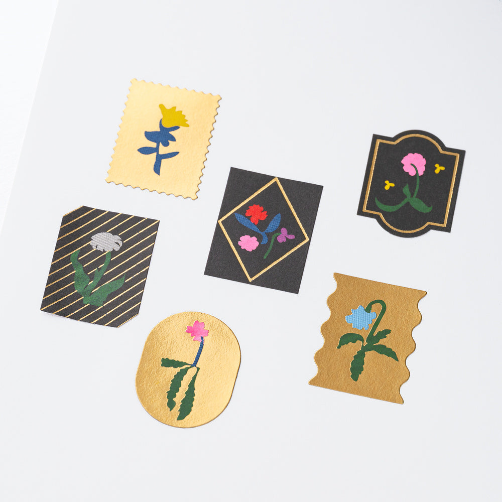 Six decorative Yoshie Watanabe stickers with gold foiling and colorful flower motifs on white background