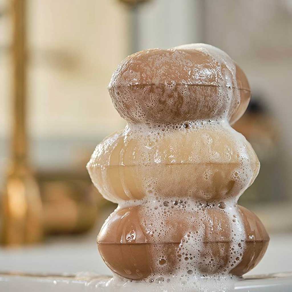 Stack of brown soap bars with bubbles on a white surface