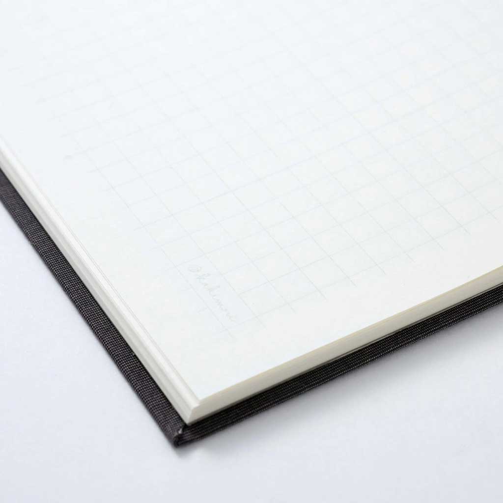 Close-up of gridded notebook with black binding on a light gray background
