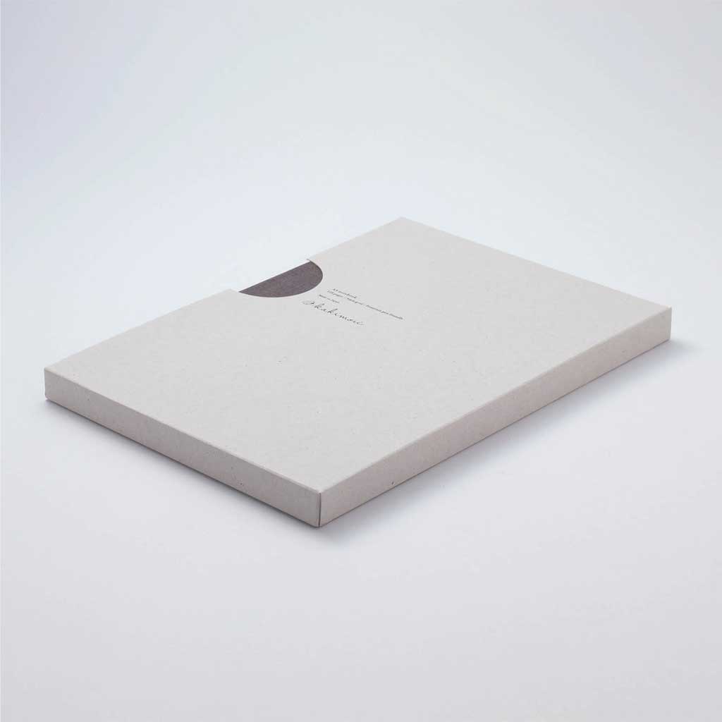 Grey notebook in light grey kraft packaging on light surface