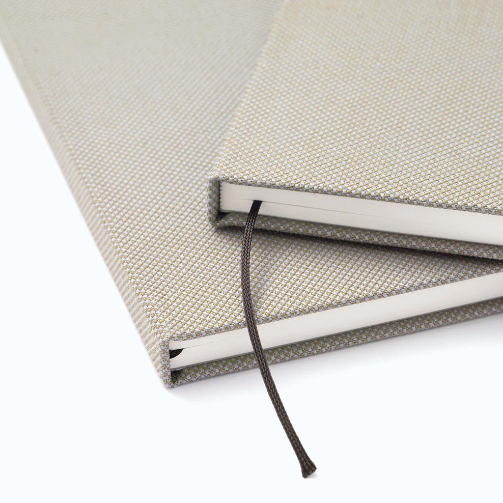 Close-up of two notebooks with woven covers and stranded bookmarks.