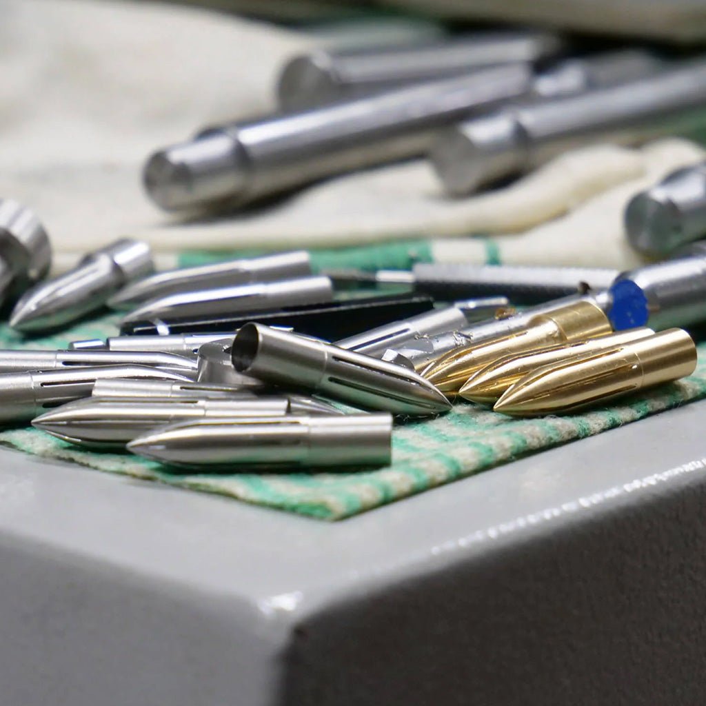 Collection of Kakimori stainless steel and brass nibs on factory table