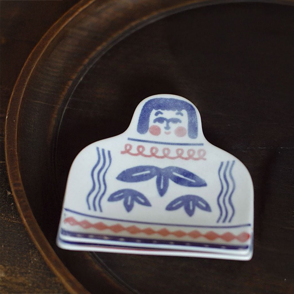 A hand-painted ceramic dish sitting on a wooden plate.
