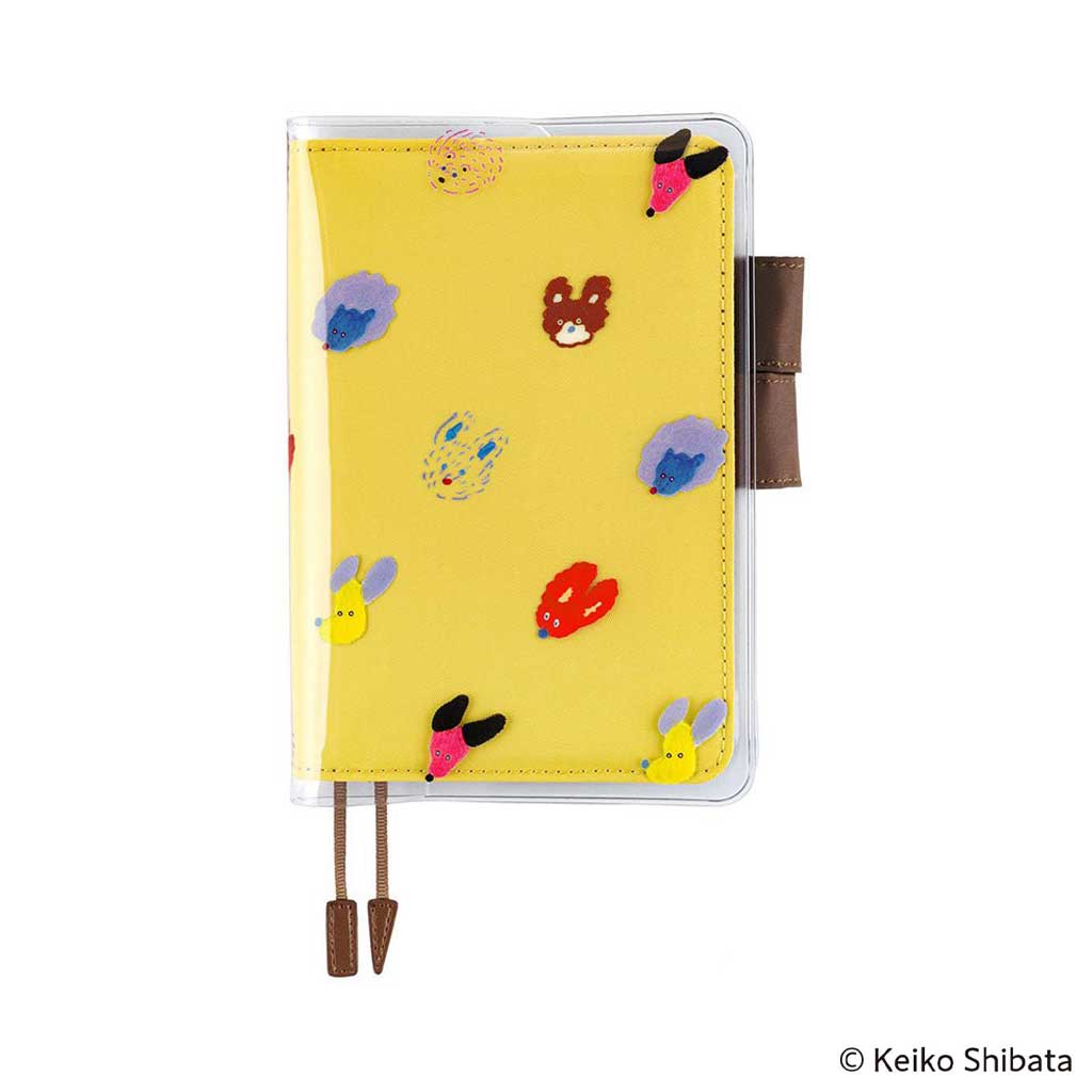 Clear cover on cover with dog illustrations on top of yellow fabric cover for Hobonichi Techo A6 planner on white background