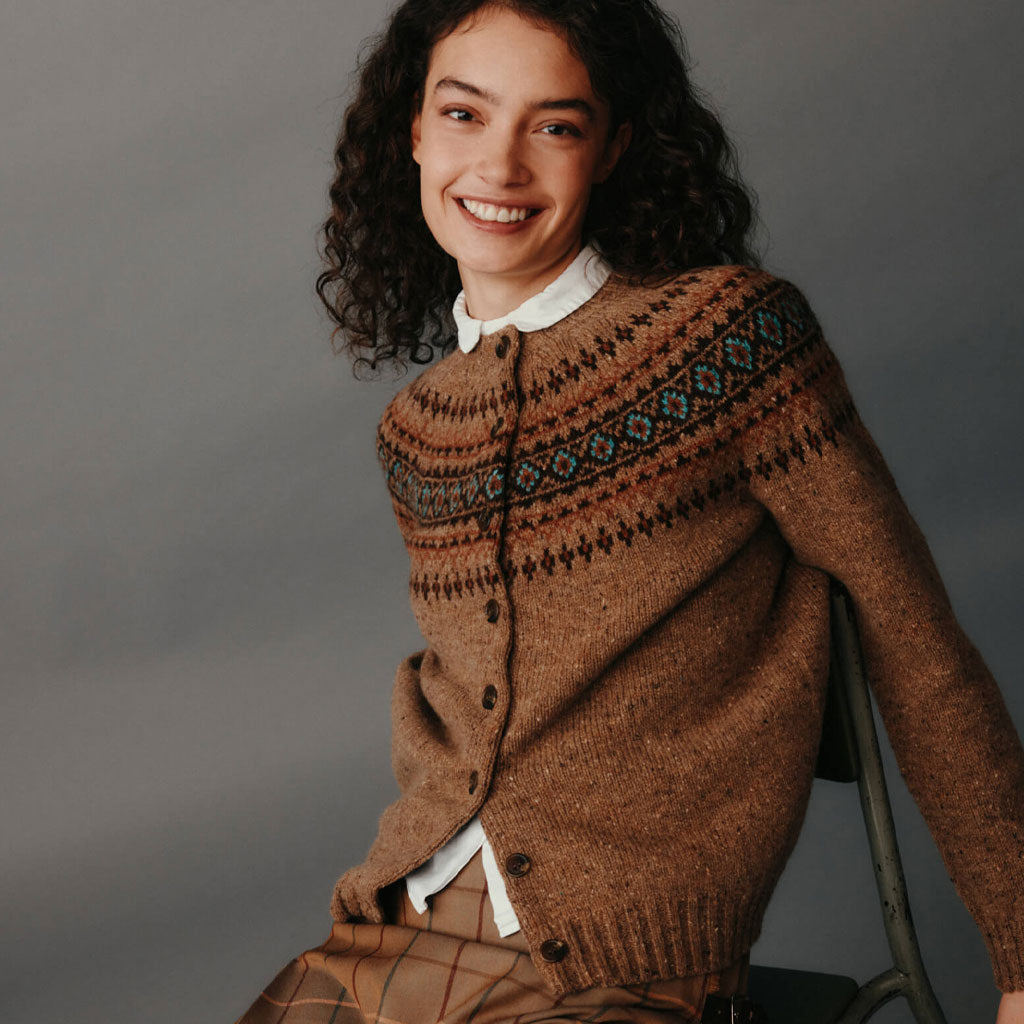 Woman wearing a brown patterned sweater against a gray background.