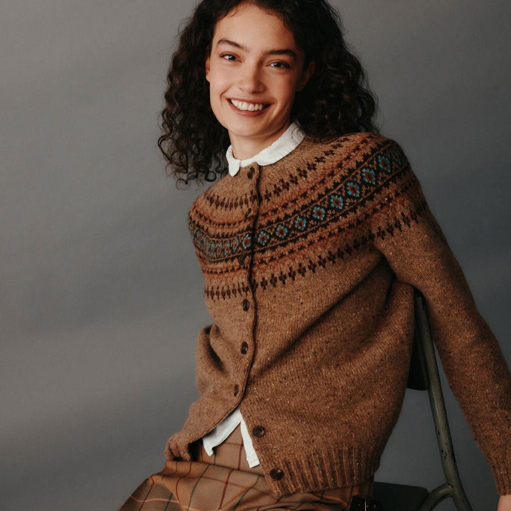Woman wearing a brown patterned sweater against a gray background.