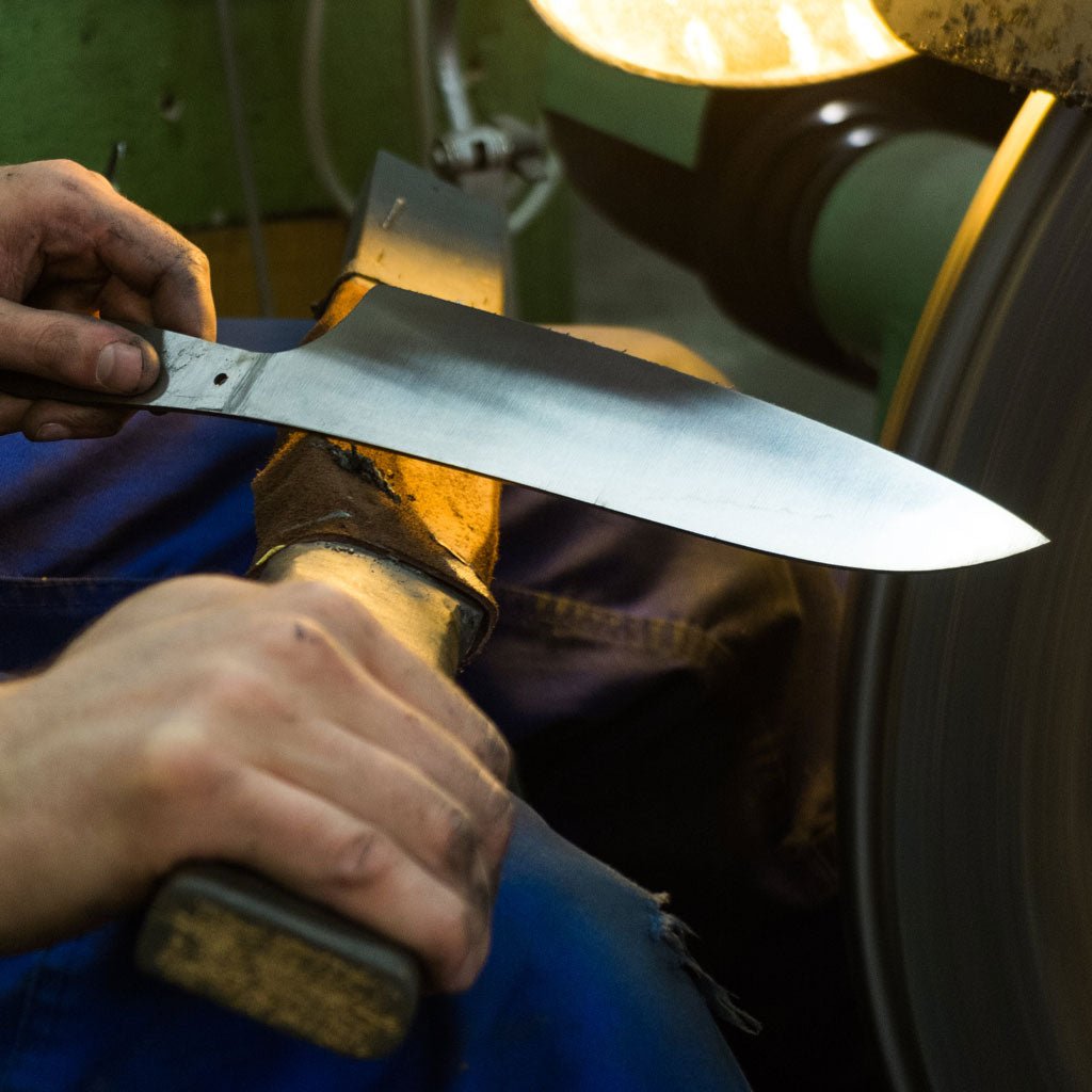 Person holding a large knife blade in a workshop setting