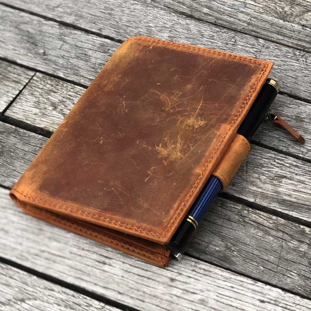 Brown leather wallet insert with a pen on a wooden surface