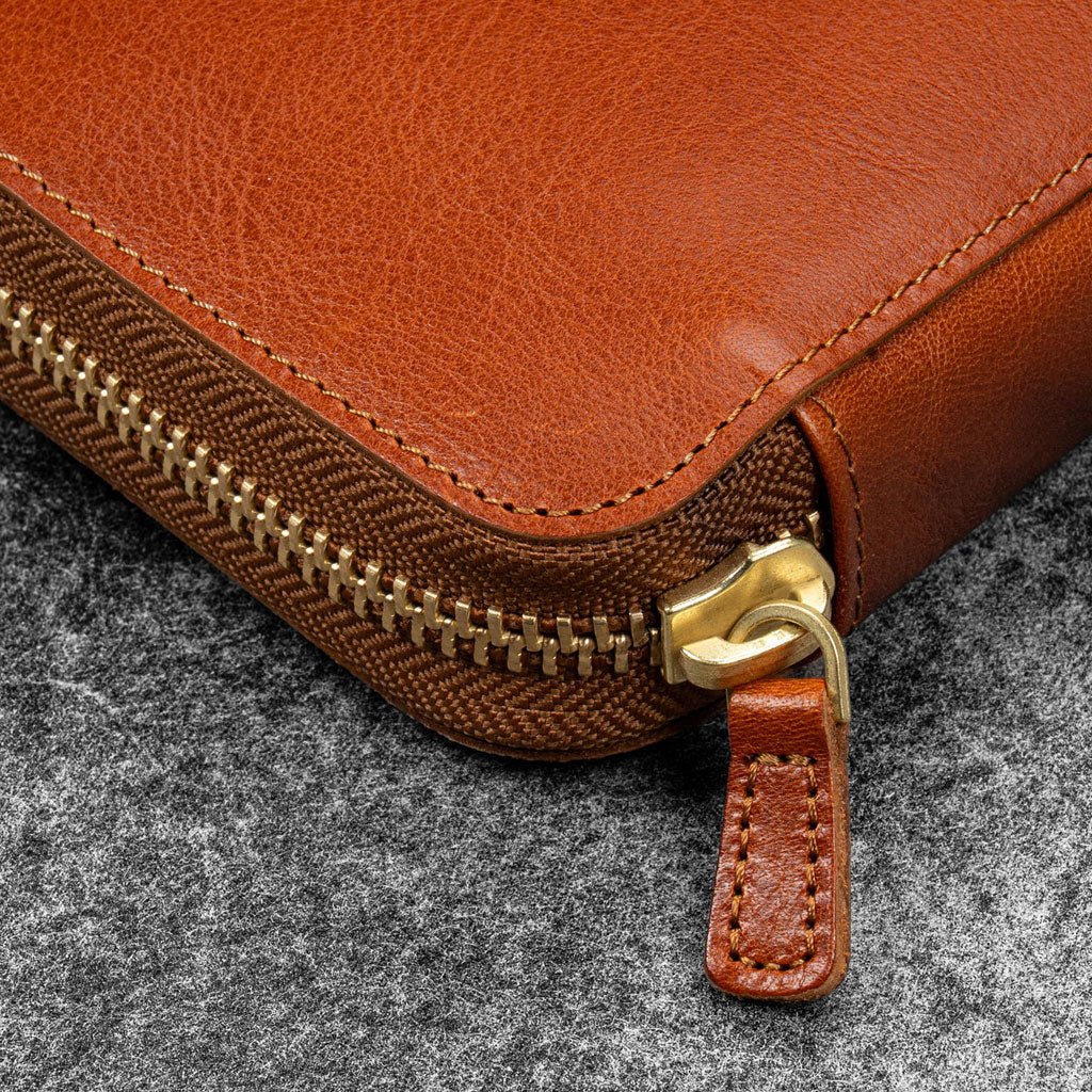 Brown leather zip pen case closed against dark background