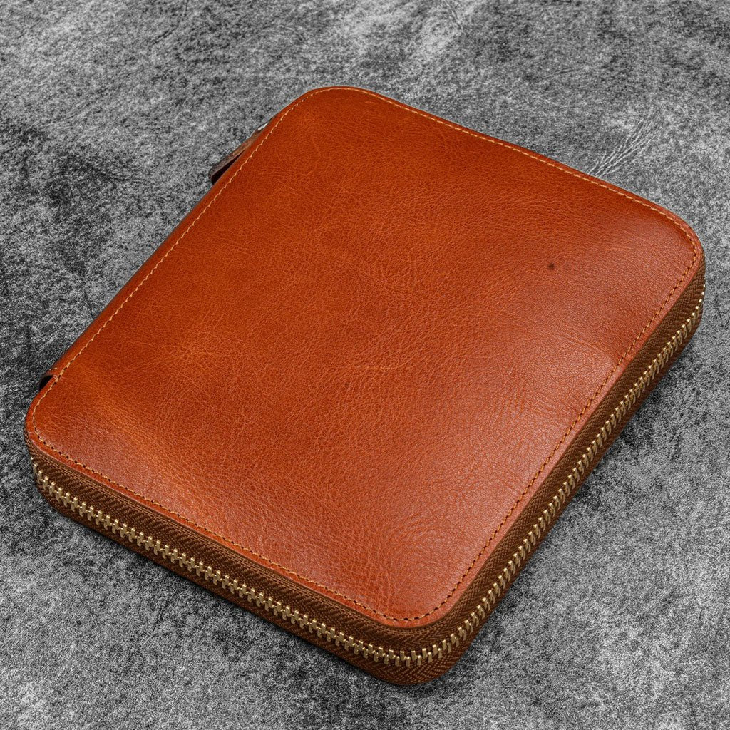 Brown leather zippered pen case on a gray textured background