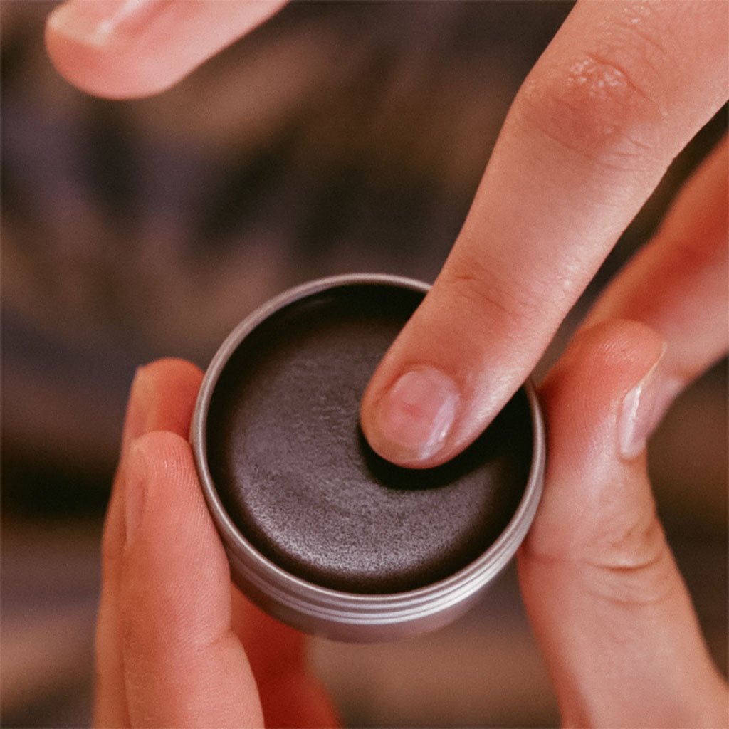 A person dipping their finger in the lip and cheek stain