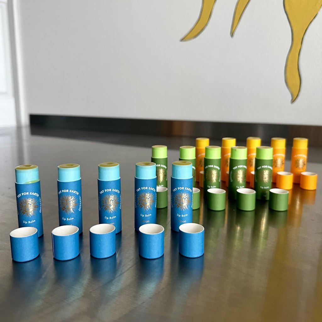 Collection of blue, green, and orange lip balms on a reflective surface.