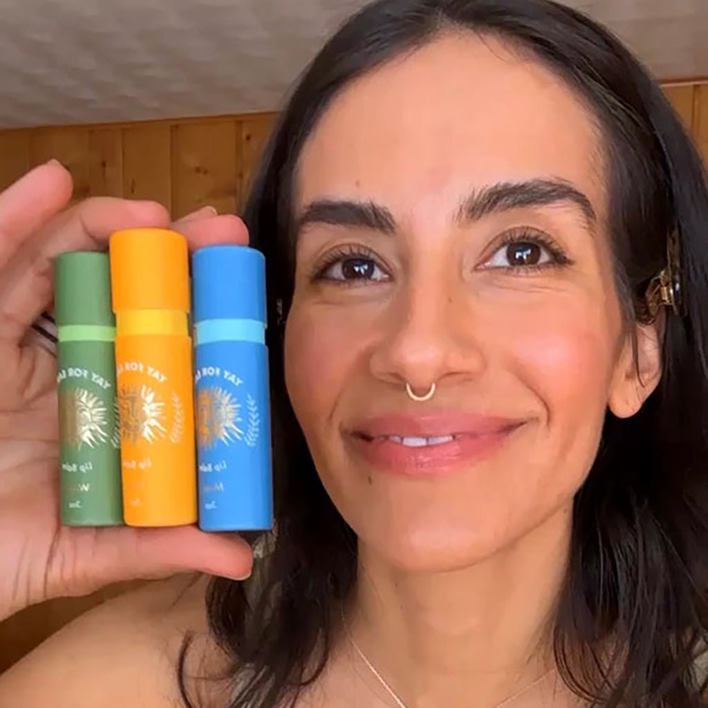Woman holding three colorful lip balm products in front of her face
