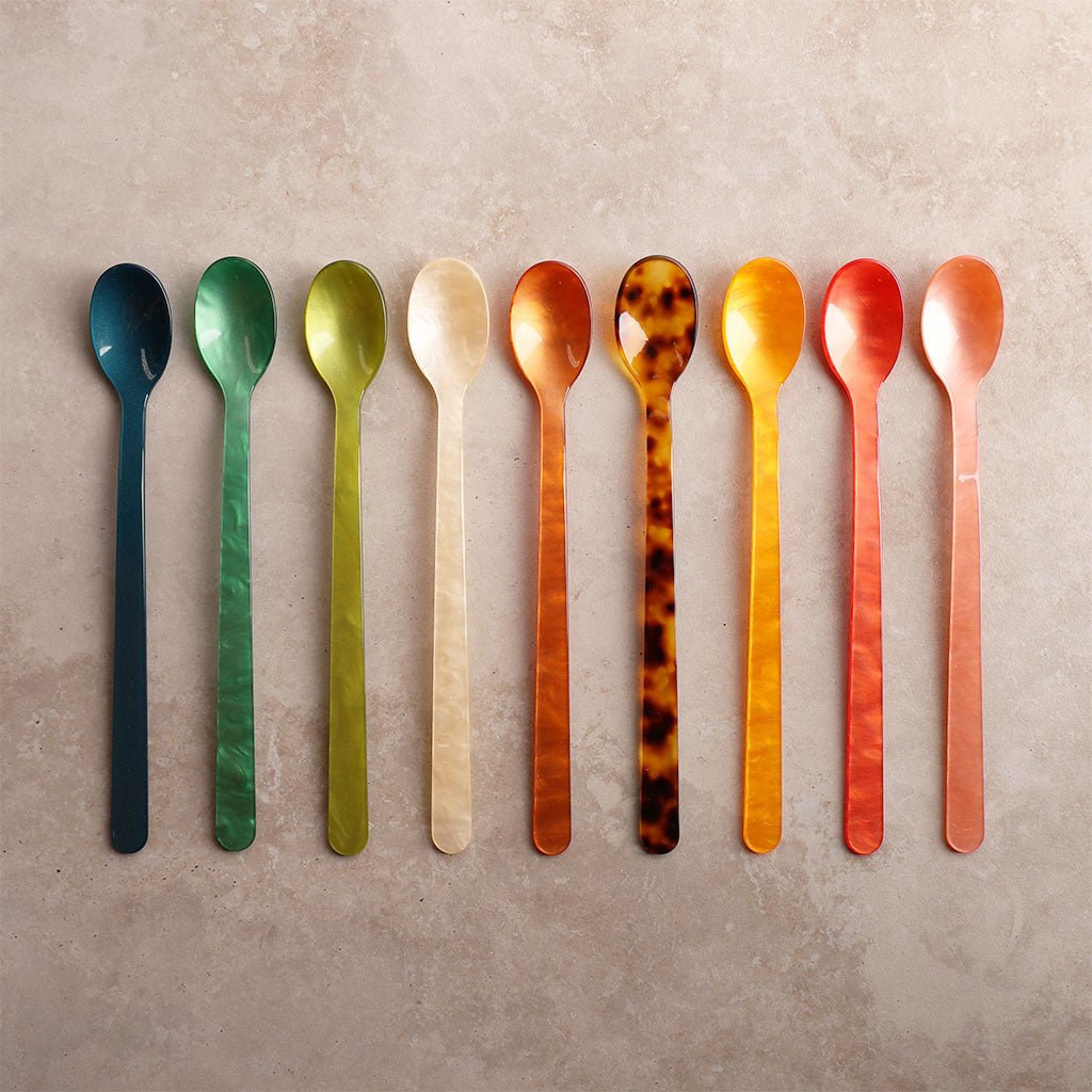 Set of colorful spoons arranged in a row on a textured surface