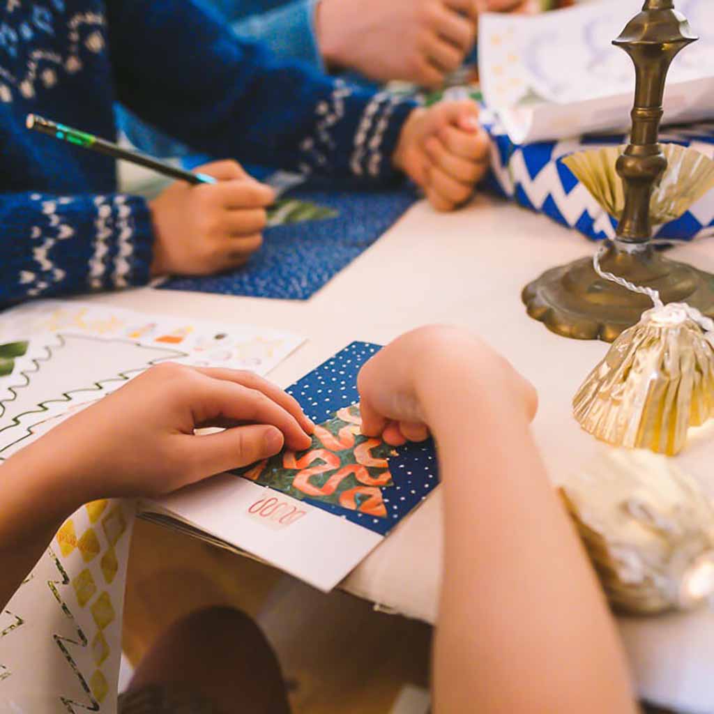 Children's hands interacting with a colorful card on a table with decorative items.
