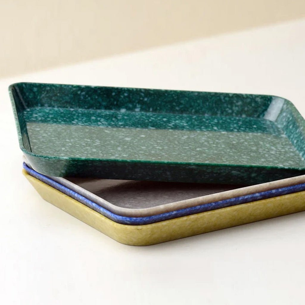 Four rectangular ceramic trays stacked slightly offset on a light surface