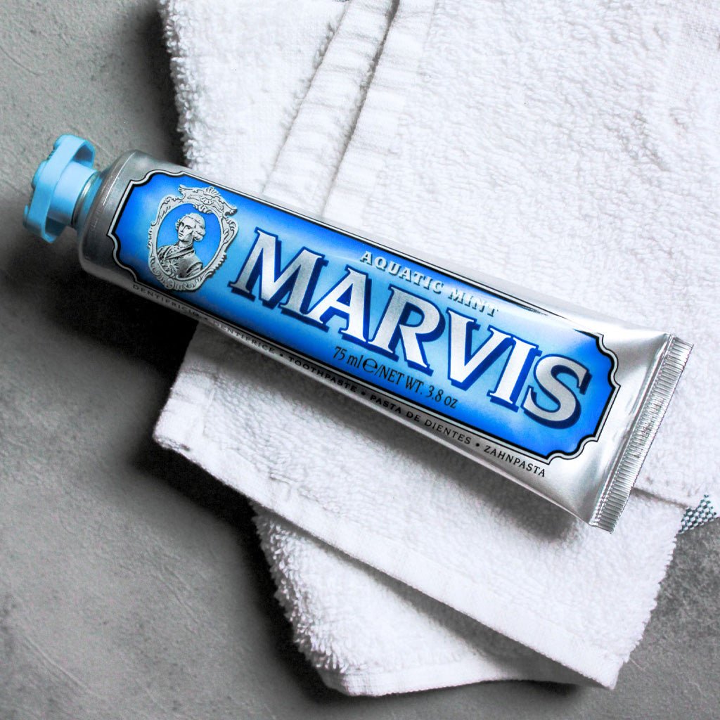 Blue Aquatic Mint Marvis toothpaste tube on top of white towel.