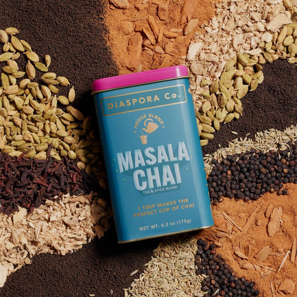Diaspora Co. Masala Chai tea spice blend canister surrounded by spices on a textured surface