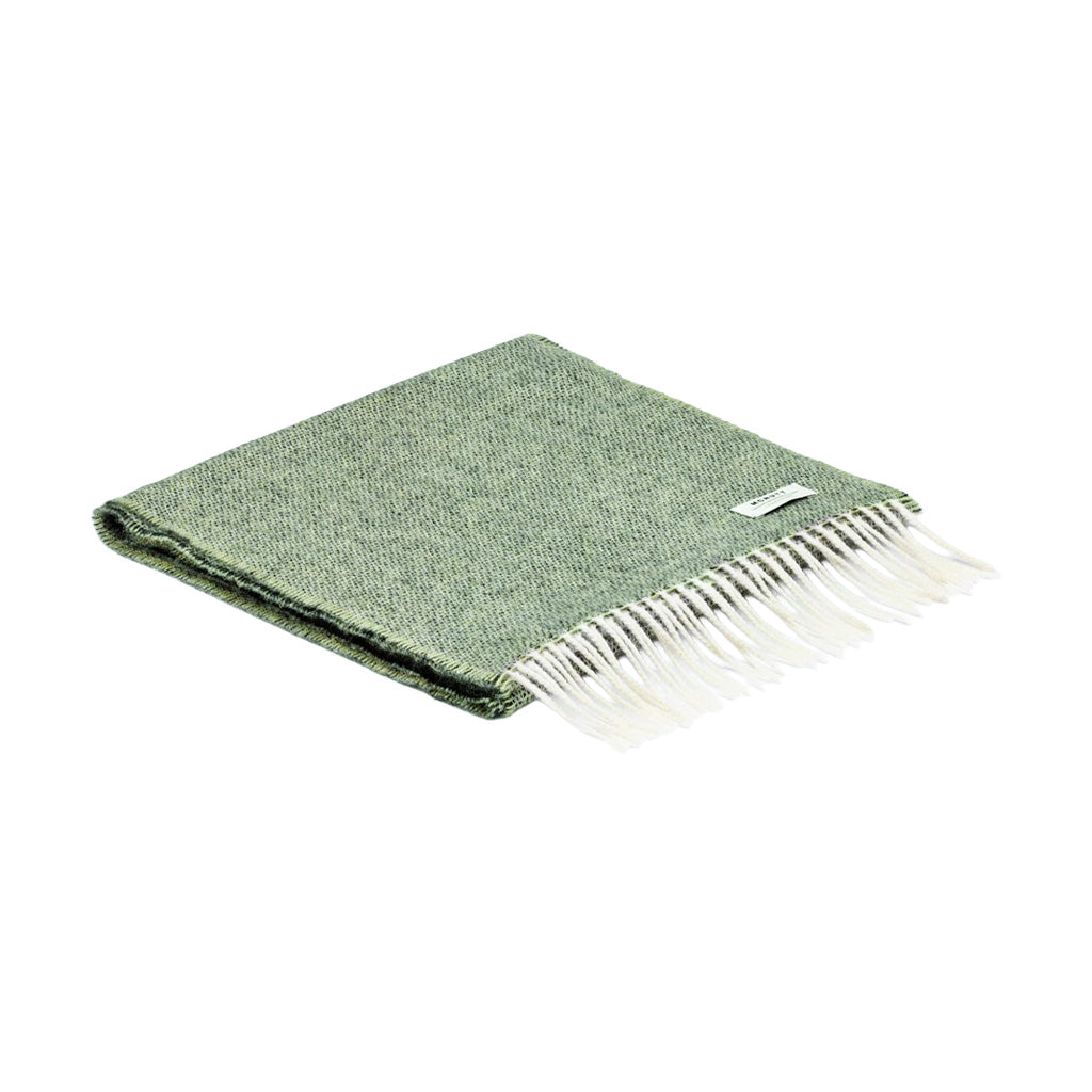 A folded green merino wool scarf with white fringe.