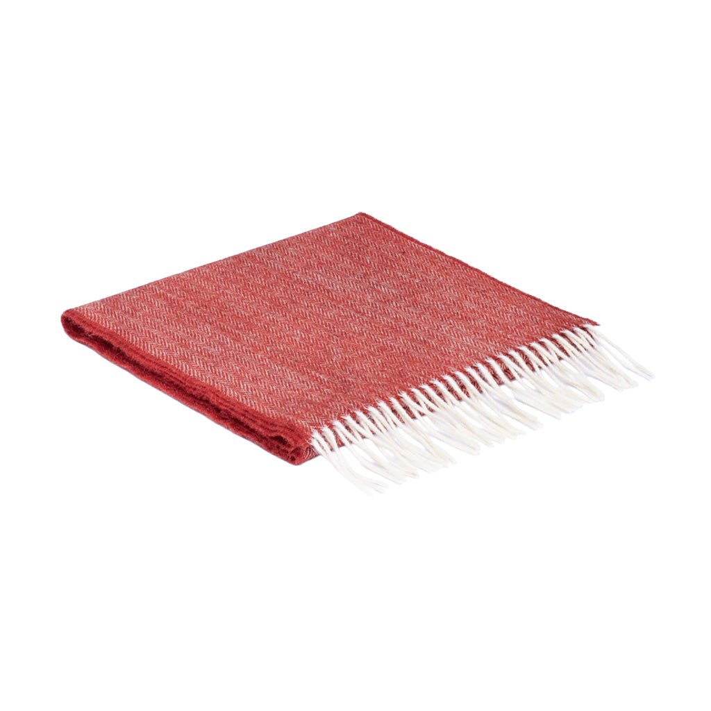 A folded red woven scarf with white fringe, displayed on a clean white background.