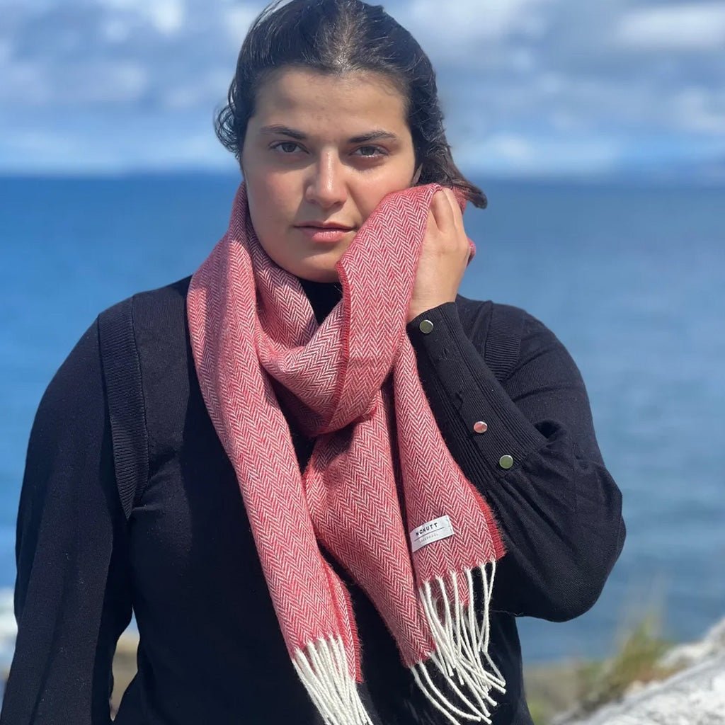 A woman wearing a red lambswool scarf in front of ocean background.