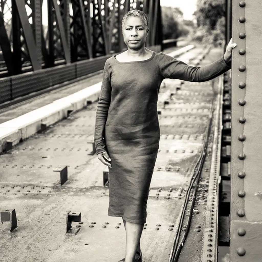 Woman wearing merchant and mills sewn clothing against city bridge background
