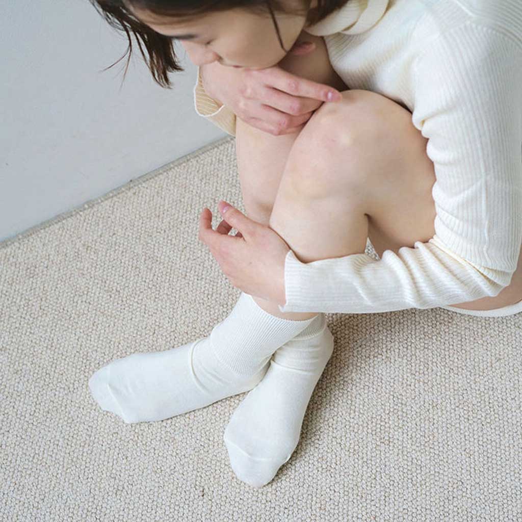 Person wearing white socks sitting on a carpeted floor.