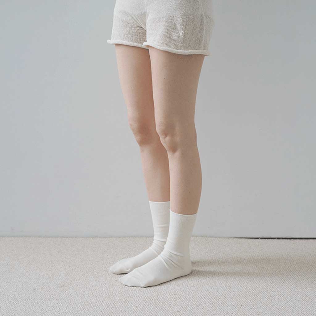 Person wearing white socks and light-colored shorts on a neutral background