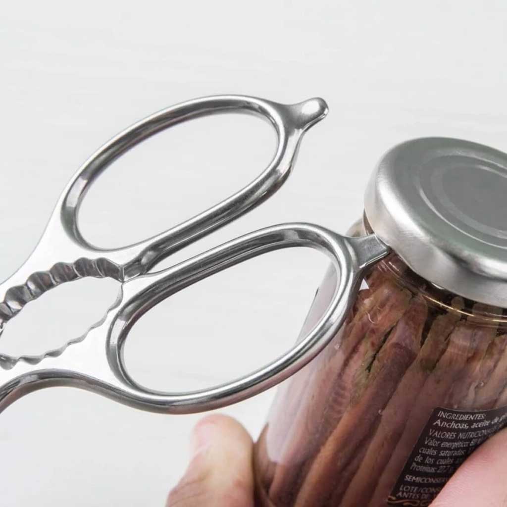 Metal can opener being used on a jar with a white background