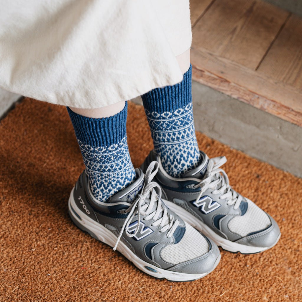 Model wearing blue and white socks with pair of gray shoes.