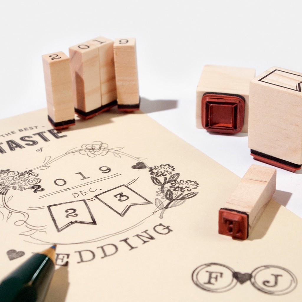 Wooden wedding year stamps with red ink pads arranged on a cream paper sheet, with part of a green pen visible at the bottom left.