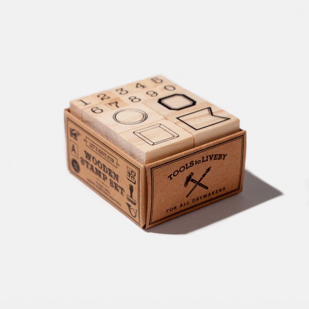 Set of wooden stamps with numbers and decorative frame designs in kraft packaging on white background