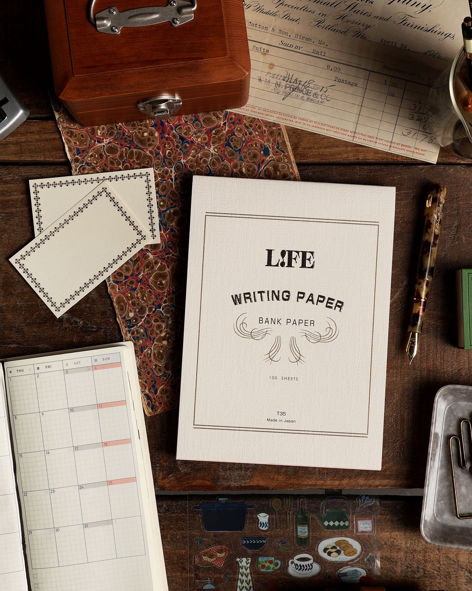 Assorted writing supplies arranged on a wood surface.