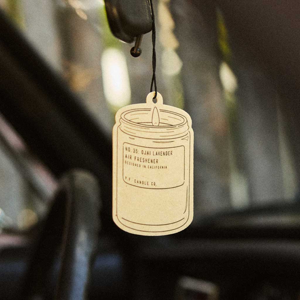 Car air freshener hanging from a car's rearview mirror with a blurred background