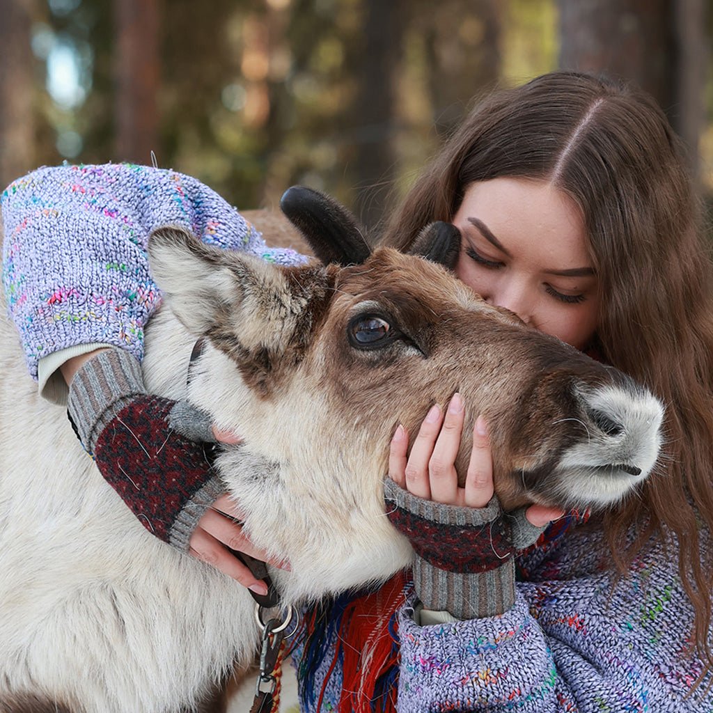 Model wearing wool mittens and petting animal.