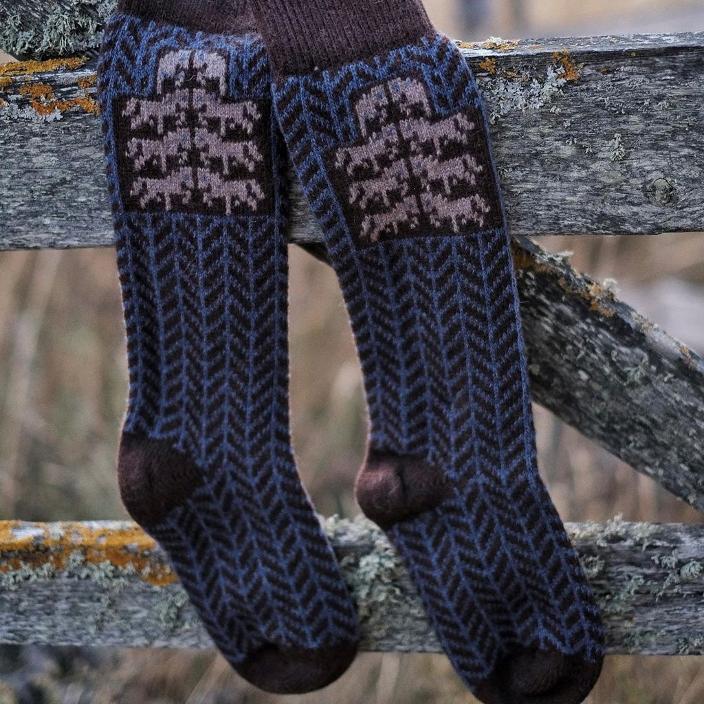 Pair of wool socks hanging on wooden fence.
