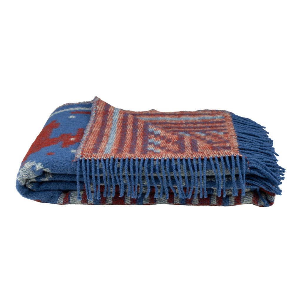 Folded wool blanket with red and blue pattern and fringe.