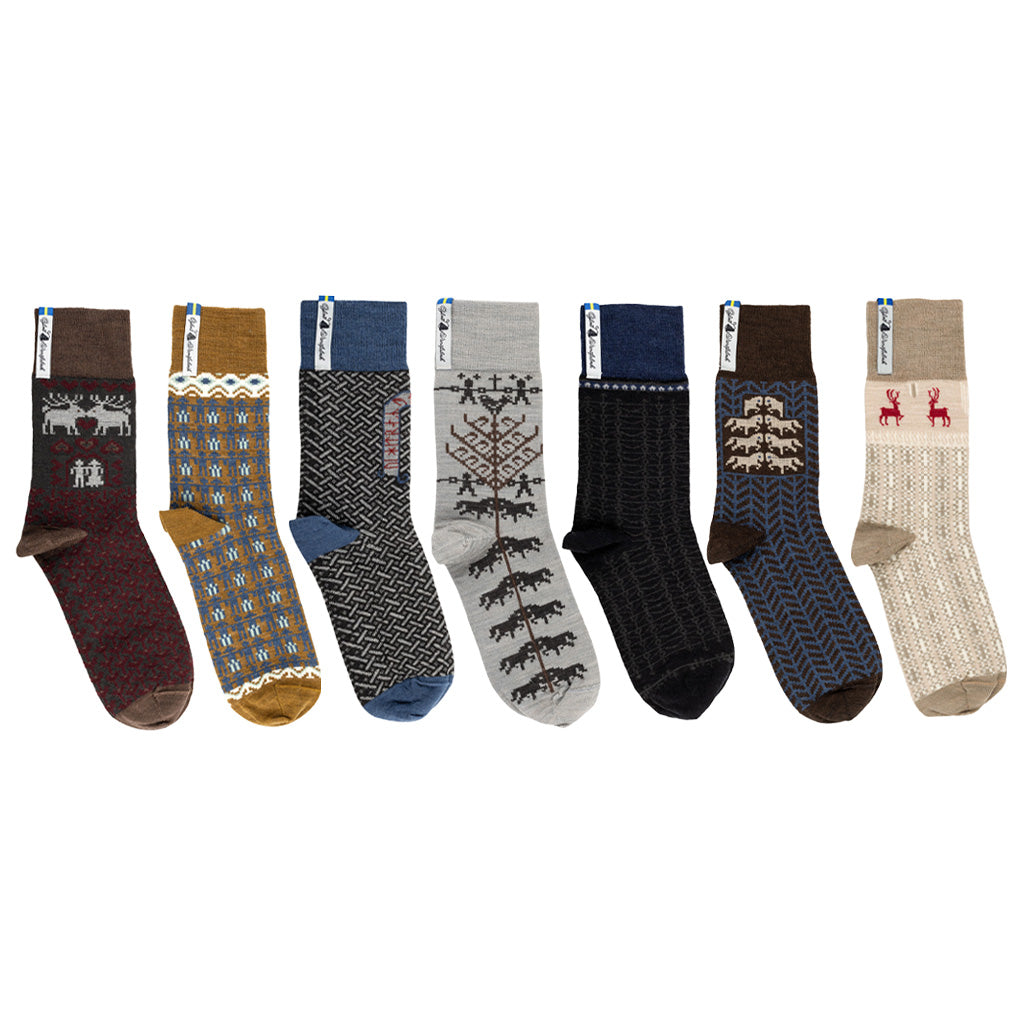 Seven patterned merino wool socks in different Nordic designs on white background.
