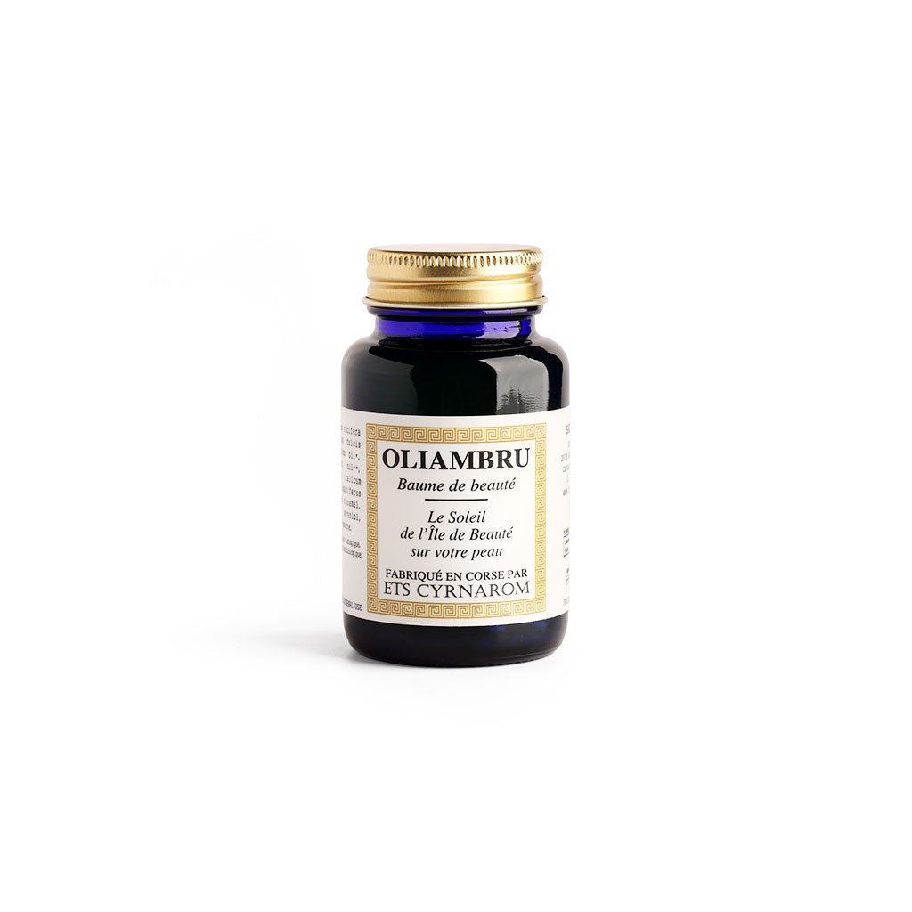 Dark blue glass bottle of Oliambru beauty balm with a gold screw cap and cream label, photographed on a white background.